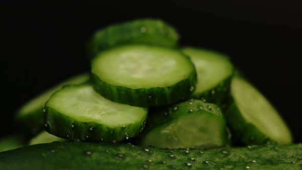 Sliced Fresh Green Cucumbers For Salad With Vitamins Rotate On A Black Background