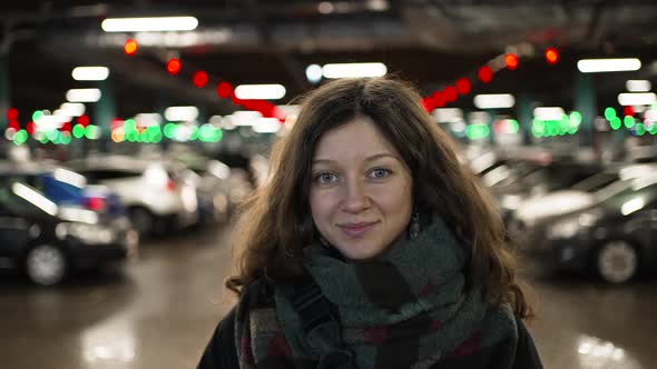 Brunette Woman Poses Looking Into Camera on Car Parking alt
