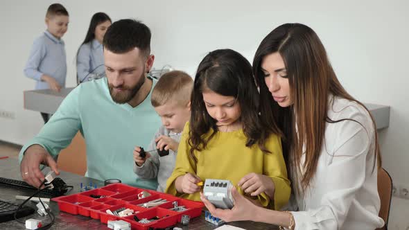 Family with Children in a Robotics Club Makes a Robot Controlled From a Constructor alt