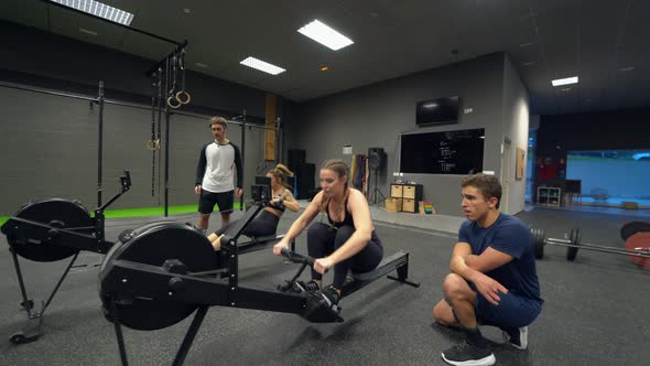 Athletes exercising on rowing machines at gym