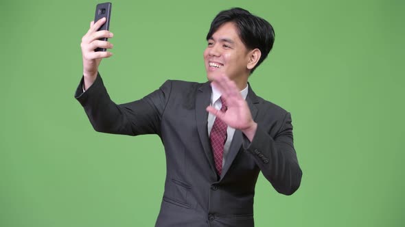 Young Handsome Asian Businessman Using Mobile Phone alt