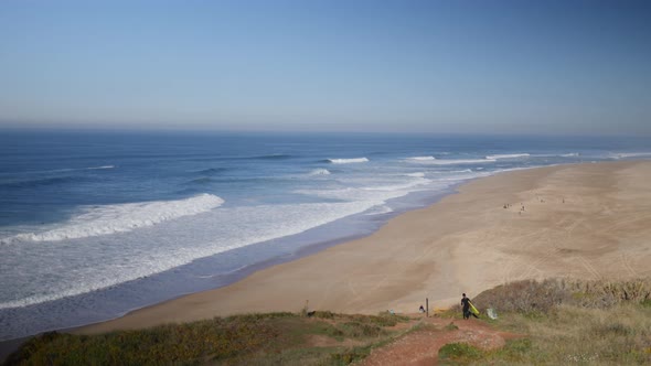 Surfer heading down the cliff in Praia do Norte, Nazare alt