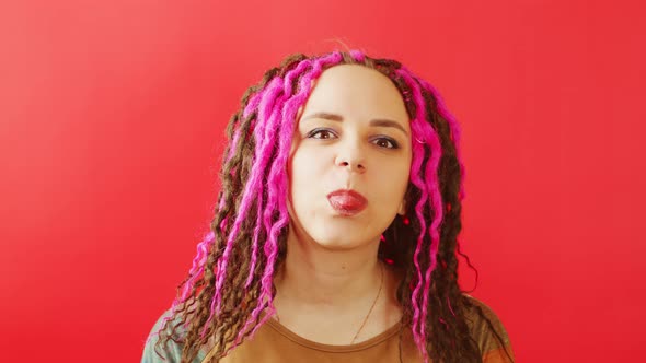 Young Female with Dreadlocks Looking at Camera and Showing Tongue alt