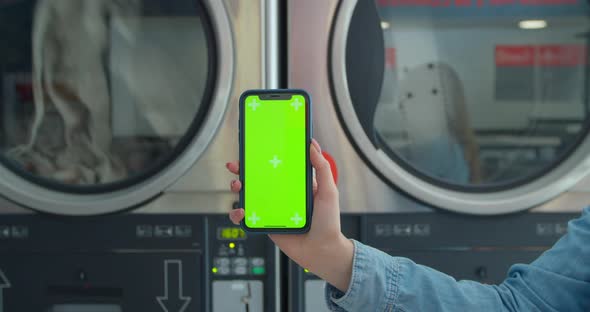 Close Up. Smartphone with Green Screen at Public Laundry. Chroma Key. Close Up. Self-service Public alt