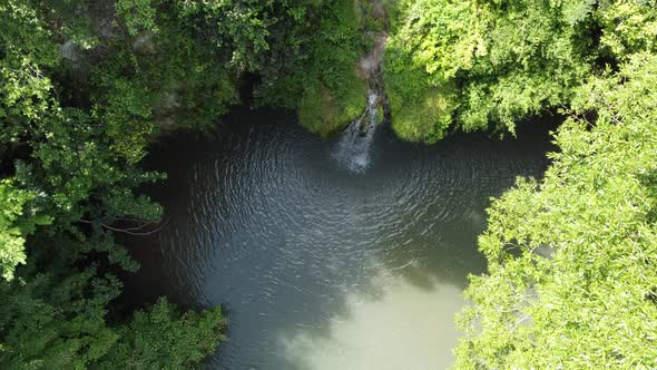 aerial view of a beautiful waterfall with blue lake in the forest.