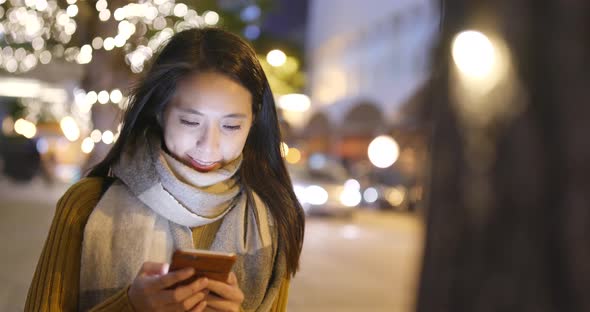 Woman look at mobile phone in city at night alt