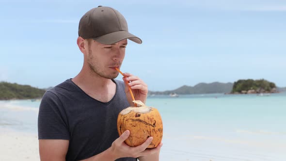 Man Drinking Coconut On Tropical Beach