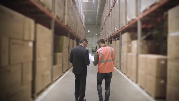 Worker and businessman with clipboard in warehouse alt