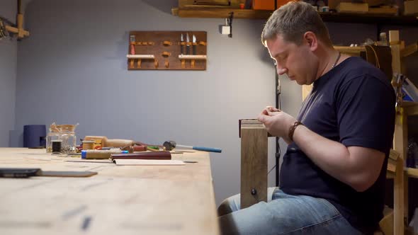 The Man with the Leather Needle To Sew in the Workshop. He Makes a Purse for Individual Design alt