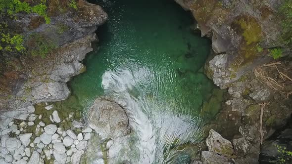 Aerial top down slow motion of Rio Azul stream flowing surrounded by rocks and vegetation, El Bolsón alt