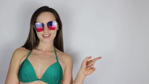 An attractive young slim sexy woman in a green bikini and sun glassless looking shocked