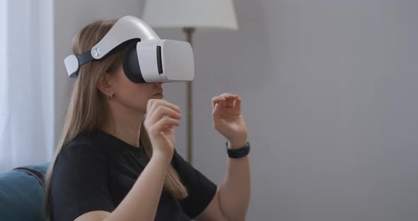 Young Woman with HMDdisplay on Head Is Viewing Photos in Virtual Reality Gesticulating Hands for alt