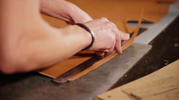 Leather Craftsman Cuts the Edge of the Product with a Knife so That It Is Even alt