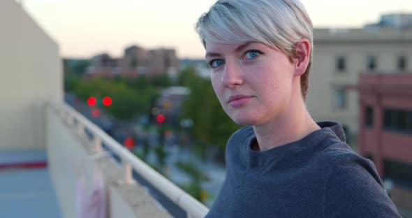 Happy flirtatious caucasian white girl looking into camera smiling from rooftop, then looks away wit alt