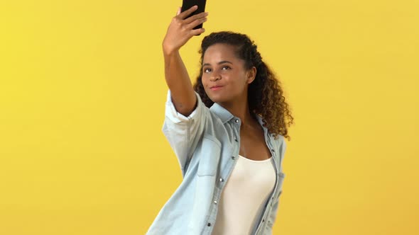 Happy smiling African American woman using mobile phone and taking selfie