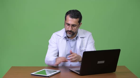 Handsome Persian Bearded Man Doctor Multitasking at Work