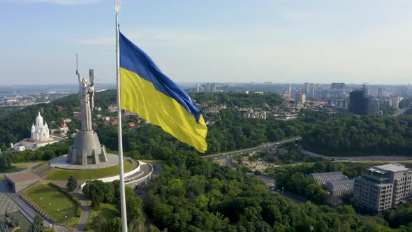 Aerial View of the Ukrainian Flag Waving in the Wind Against the City of Kyiv alt