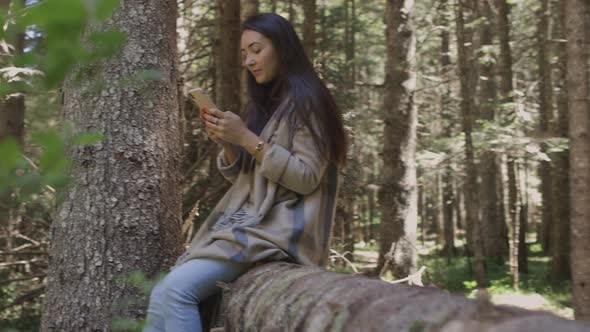Pretty Woman Using Smartphone in Forest Outdoors alt