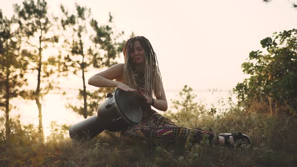 Beautiful Young Hippie Woman with Dreadlocks Playing on Djembe alt