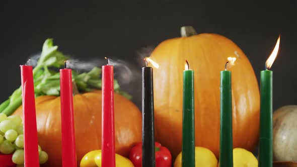 Composition of seven candles being blown off over halloween pumpkins and vegetables alt