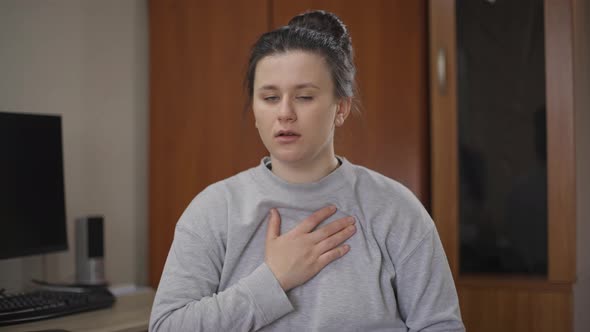 Unwell Caucasian Young Woman with Shortness of Breathe Touching Chest Inhaling with Shocked Facial alt
