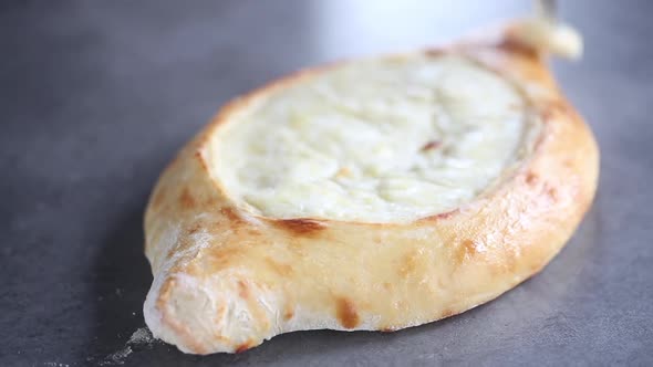 Baker greases khachapuri pie with butter