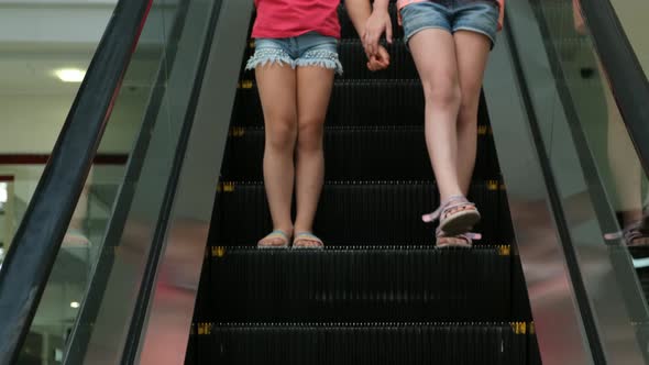 Two little girls go down the escalator in the Mall