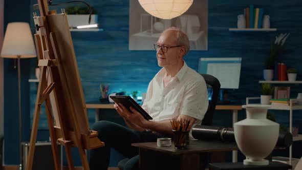 Retired Artist Using Tablet to Browse Inspiration Model on Internet alt