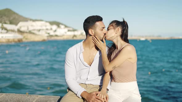 Smiling Hispanic Couple Talking While Kissing on Embankment alt