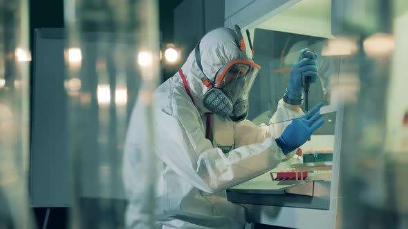 Researcher Is Analyzing a Glass Tube with Liquid Substance During Coronavirus Pandemic. alt