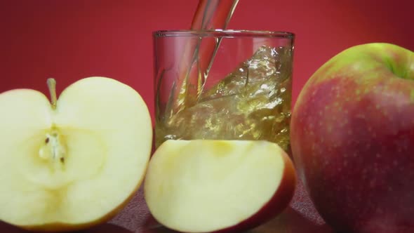 Fresh Apple Juice Is Poured in a Glass on the Red Background alt