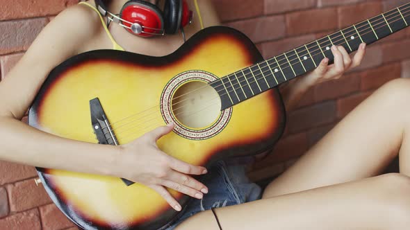 Hands of Anonymous Female Picking Strings While Playing on Acoustic Guitar alt