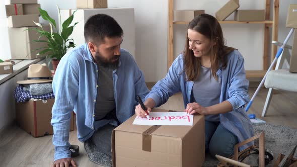 Young Married Couple Moves to a New House Packing Boxes with Things Carrying a Bedroom Box alt