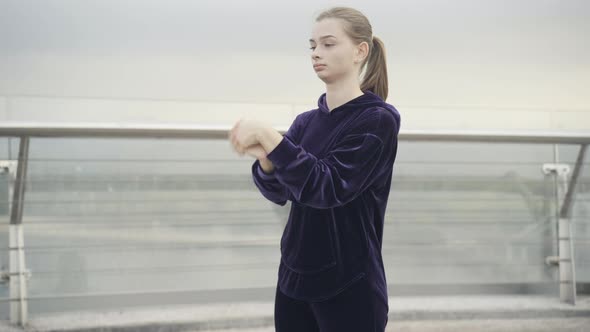 Middle Shot of Confident Fit Caucasian Woman Stretching Hands Before Morning Training on Cloudy Day alt
