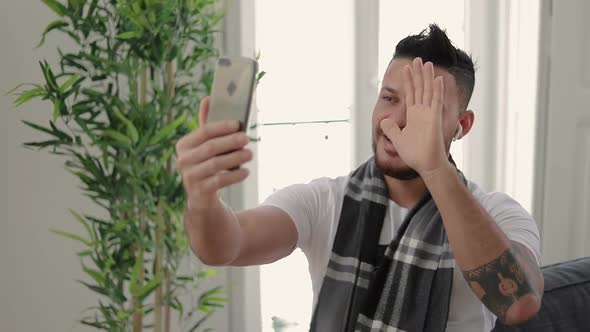 Handsome Smiling Tattooed Man Having Video Call Through Smartphone. alt