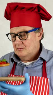 Senior Adult Chef Caucasian Ethnicity in Red Chef Hat Tasting with Enjoying Bruschetta alt