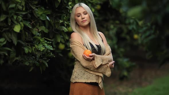 Woman in Brown Knitted Pullover with Ripe Clementines in Her Hands