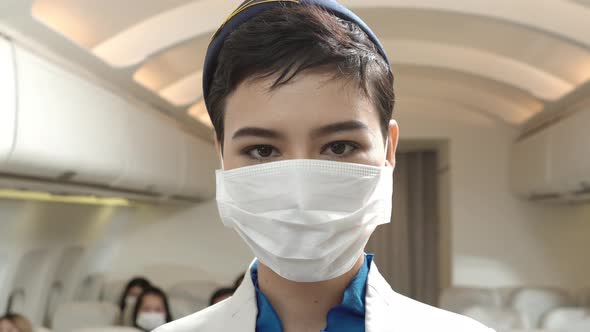 Female flight attendant wearing medical protective mask to prevent Coronavirus on plane
