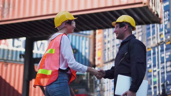 Engineer and foreman worker team planning control loading containers box and handshake at cargo