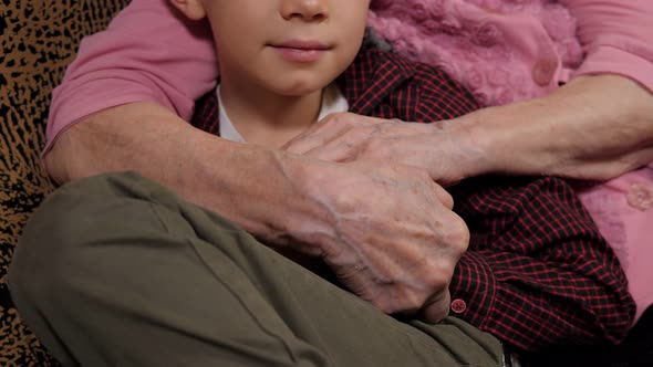 A Grandmother Embracing Her Little Grandson with Her Wrinkled Hands alt