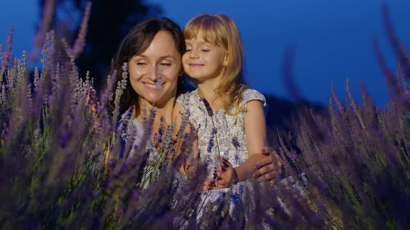 Mother and Girl Daughter Kid Kissing Laughing in Aromatic Flowers Lavender Field Garden at Night alt