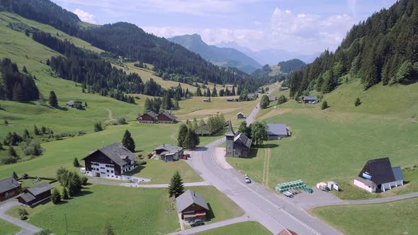 Aerial View of a Valley in Switzerland with Chalets and a Mountainous Landscape alt