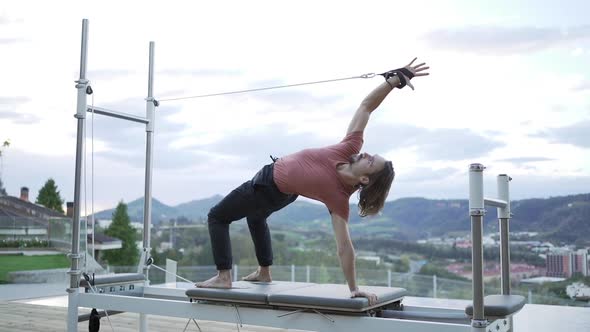 Man doing yoga in Wheel pose on pilates reformer alt