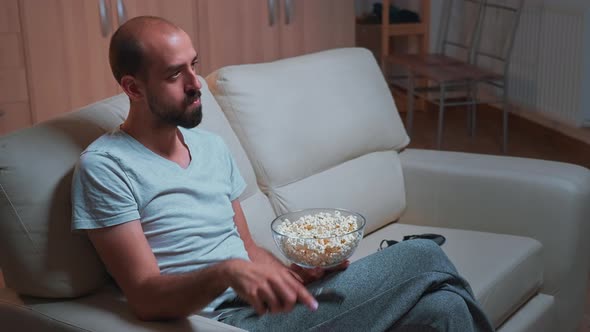 Caucasian Male Chilling on Sofa with Popcorn Bowl in Hands While Watching Movie Series alt