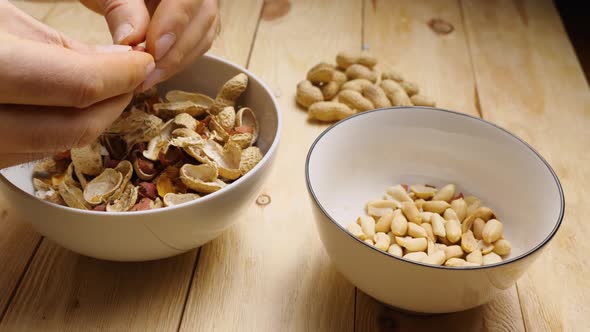 Close-up of male fingers peeling roasted peanuts from their shells alt