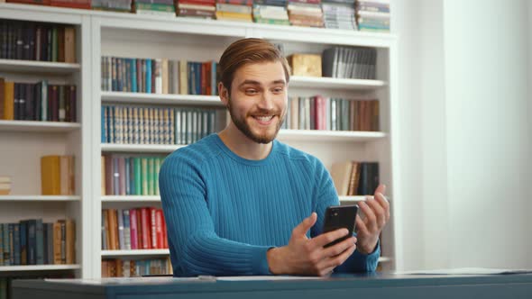 Video chat of a smiling man with a student on a mobile phone alt