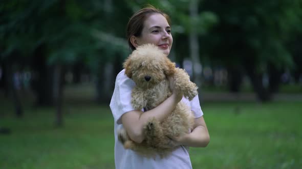 Woman with Toy Poodle Walking in a Park