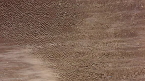 A low, top down shot over the beach at Kaiser Park, as the camera hovers. It's a windy day you see alt