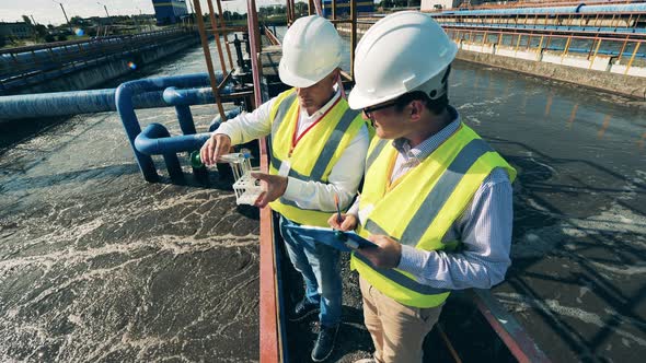 Two Specialists Taking Water Samples at a Sewage Treatment Plant alt