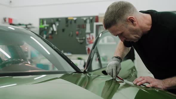 Process of Vinyl Wrapping a Car in Khaki Green Color Cutting the Wrap